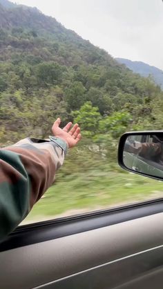 a person is holding their hand out the window of a car