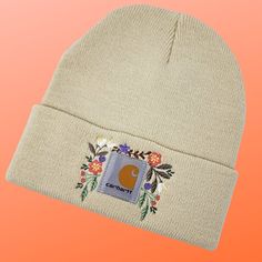 a beanie with the letter c on it and flowers in front of an orange background