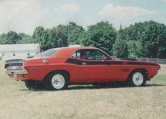 an old red car is parked in the grass