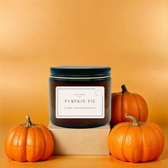 three pumpkins sitting next to a jar of pumpkin pie