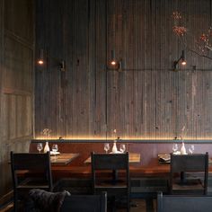 an empty restaurant with wooden walls and black chairs in front of the dining room table