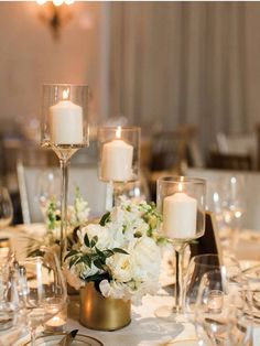 white flowers and candles are on the centerpieces at this elegant wedding reception table