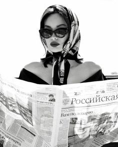 a woman in sunglasses reading a newspaper