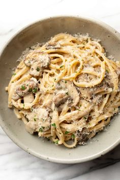 pasta with mushrooms and parmesan cheese in a bowl on a marble countertop