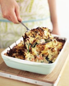 a person scooping food out of a casserole dish on a cutting board