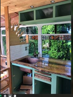 a kitchen area with sink, window and shelves in the back wall is painted teal