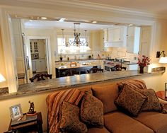 a living room filled with furniture next to a kitchen