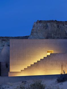 the stairs are lit up at night in front of a large concrete structure with windows