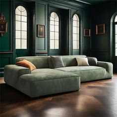 a living room with green walls and wood flooring is pictured in this image, the couch has two pillows on it