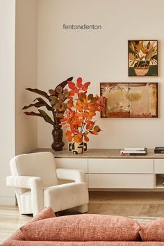 a living room with two white chairs and a vase filled with flowers on top of a table