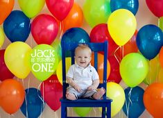 a baby sitting in a blue chair surrounded by balloons and saying jack is turning one