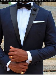 a man in a tuxedo standing on some steps