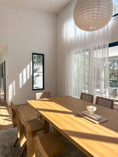 a dining room table and chairs with sunlight streaming through the windows