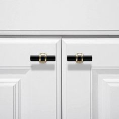 two black handles on white cabinets with gold hardware