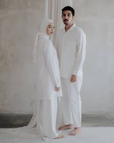 two people standing next to each other in white clothing