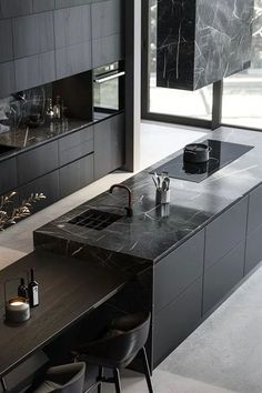 a modern kitchen with black cabinets and marble counter tops