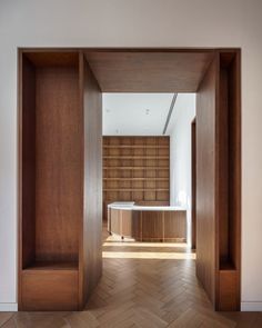 an open door leading to a bathroom with a tub in the center and wooden shelves on either side