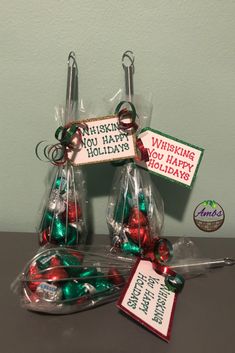 three clear bags filled with christmas candy sitting on top of a table next to a sign