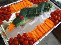 a caterpillar made out of carrots and tomatoes on a sheet of tin foil