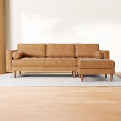 a tan leather couch sitting on top of a wooden floor next to a white rug