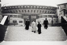 three men are walking up some steps in front of a building