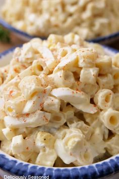 macaroni and cheese salad in a blue bowl on a table next to another dish