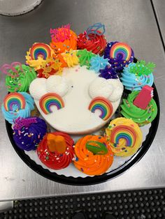 a cake decorated with rainbow icing and cupcakes