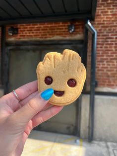 a person holding up a cookie with a face on it