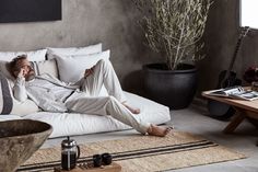 a man laying on top of a bed next to a potted plant