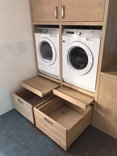 a washer and dryer in a bathroom with wooden drawers on the floor next to each other