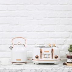 a toaster and kettle sitting on top of a counter next to a potted plant