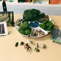 there are many small toys in the bowl on the table next to books and pictures