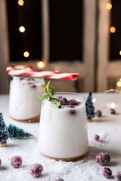 two small glasses filled with pudding on top of snow covered ground next to christmas decorations