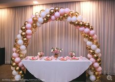 the table is set up for a baby shower with balloons and pink, gold and white decorations