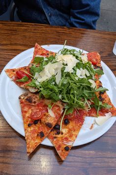 a white plate topped with slices of pizza covered in cheese and vegtables