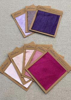 five different shades of purple and pink on top of each other in brown envelopes