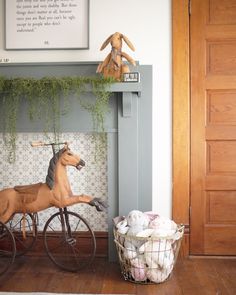 a toy horse is on top of a bicycle in front of a fireplace mantel