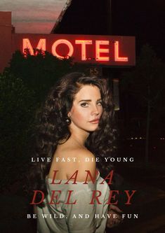 a woman standing in front of a motel sign with her hair blowing in the wind