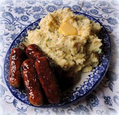 sausages and mashed potatoes on a blue and white plate