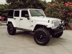 a white jeep is parked in a driveway