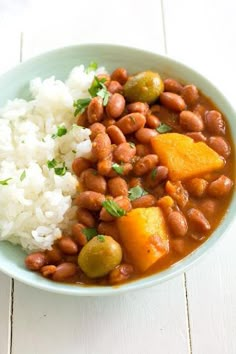 a bowl filled with beans and rice on top of a white table next to a fork