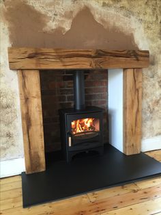 a wood burning stove sitting inside of a brick fireplace next to a wooden floor and wall