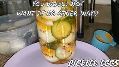 a mason jar filled with pickles and cucumbers on top of a table