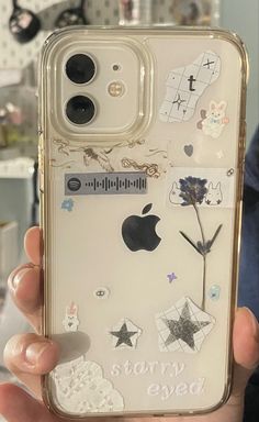 someone is holding up their phone case with stickers on it and there are other things in the back