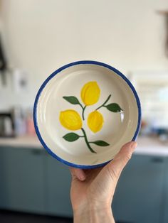 a hand holding a bowl with yellow flowers painted on it