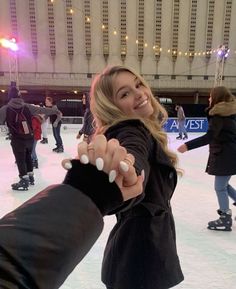 a woman on an ice skating rink pointing at the camera