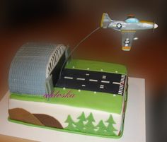 a birthday cake with a plane flying over the road and trees on it's side