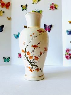 a white vase sitting on top of a table next to colorful butterflies and paper flowers