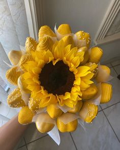 a sunflower with yellow petals and white pearls on it's head is being held by someone