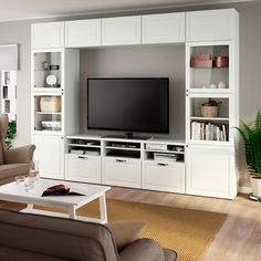 a living room with white furniture and a flat screen tv mounted on a wall unit